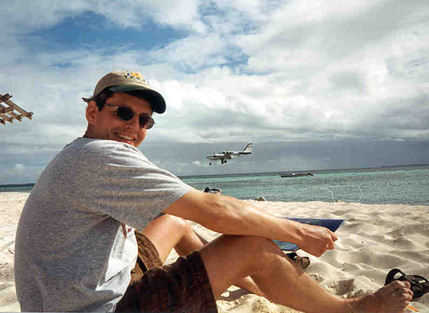 Mike sitting on the beach as our plane comes in to land